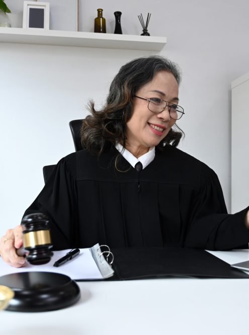 Mature female lawyer in robe gown uniform sitting front of laptop, providing law consultation and legal advice online.